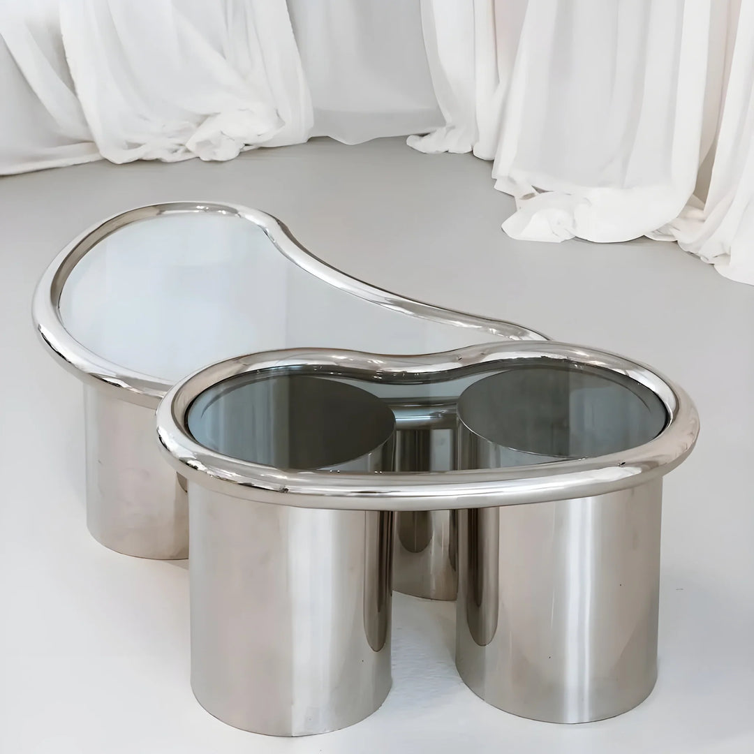 Close-up of The Willow Chrome Coffee Table With Small Gestures showcases its polished chrome legs and clear glass top.